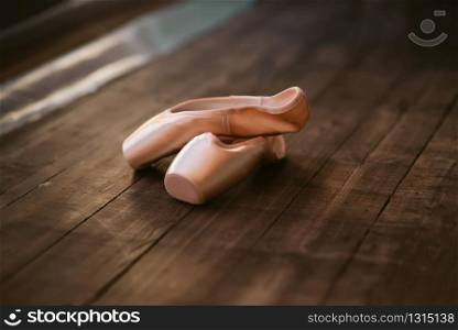 Ballet pointe shoes on the wooden floor closeup. Dance footwear concept