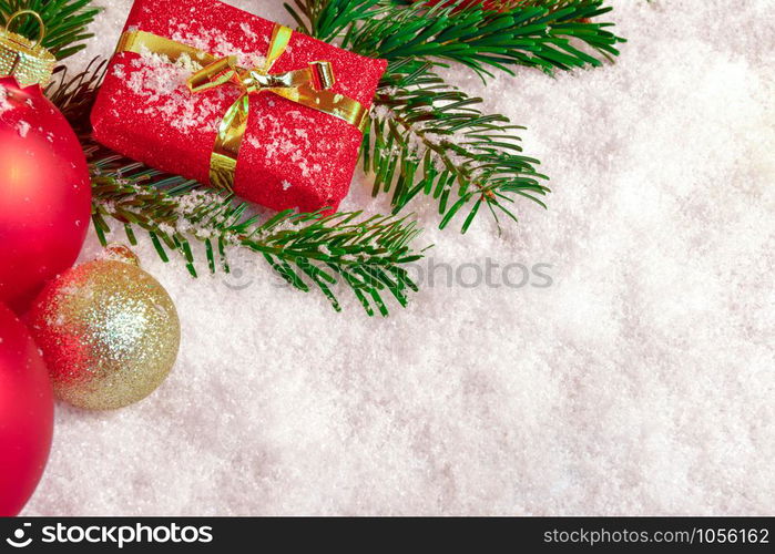 Balls, fir branch and present in the snow