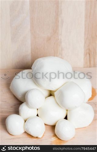balls mozzarella different size on wooden background