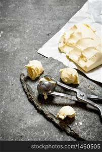 Balls of butter with a measuring scissors. On the stone table.. Balls of butter with a measuring scissors.