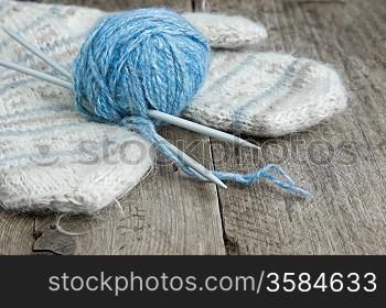 balls of yarn and mittens on a wooden background
