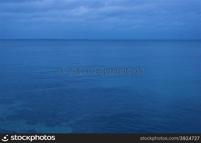 Baltic sea at night. The calm surface of the baltic sea at night with clouds and a blue cast