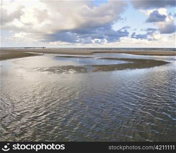 Baltic sea coastline. Clouds reflection in a wet sand. Palanga beach.