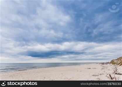 Baltic sea with sandy beach in the foreground. Water and blue clouds sky in the beckground. Baltic sea with sandy beach