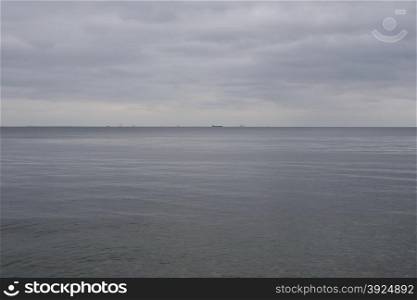 Baltic seascape with ship in distance. Baltic seascape with ship in distance and grey clouds as seen from the coast of Denmark north of Copenhagen towards Sweden