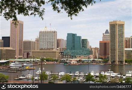 Baltimore city inner harbor showing the city skyline, ship, and pleasure craft docks and boardwalk.