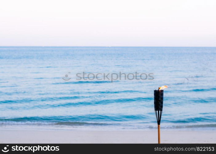 Bamboo fire torch on sunset tropical beach - Peaceful evening Thailand summer beach background concept