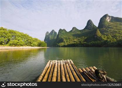 Bamboo raft in a river with a hill range in the background, Guilin Hills, XingPing, Yangshuo, Guangxi Province, China