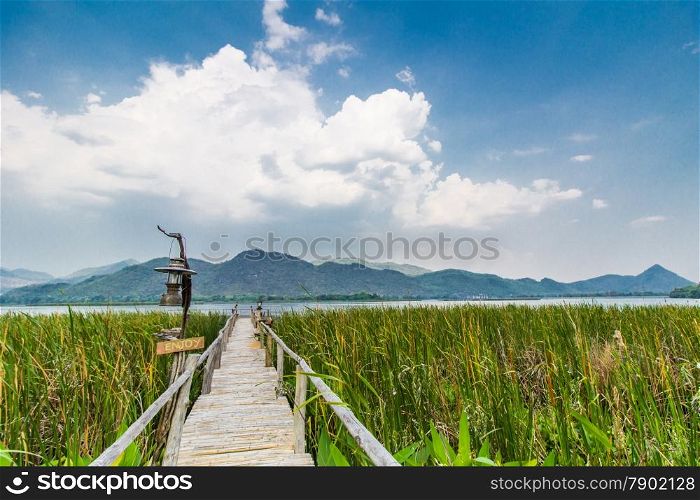Bammboo bridge ahead to reservoir with mountain and sky view in Karnchanaburi,Thailand