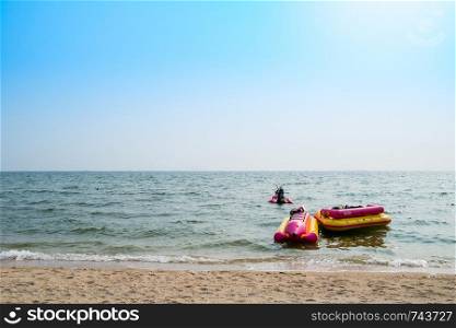 Banana boat and a rubber boat float with jet ski in the sea with blue sky.