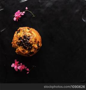 Banana Chocolate chip muffins with pink Mexican creeper flowers on black slate plate background with copy space
