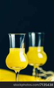 Banana flavoured liqueurs, which French call creme de banana, in grappas wineglass on dark concrete surface. European aperitif drink. Selective focus, shallow depth of the fields, copy space.