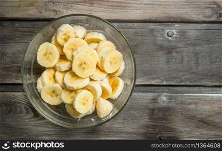 Banana slices in a glass bowl. On a black wooden background.. Banana slices in a glass bowl.