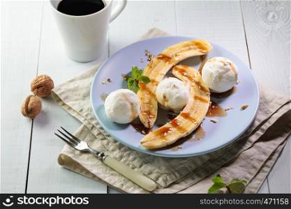 Banana split with vegan ice cream served on blue plate with cup of black coffee