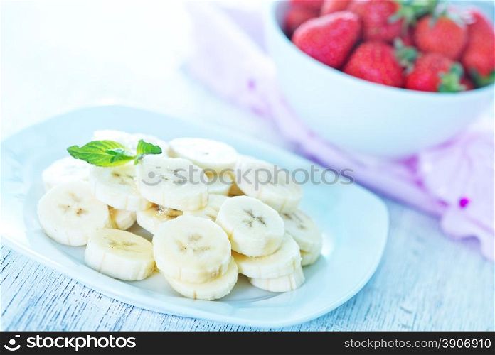 banana with strawberry on plate and on a table