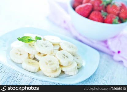 banana with strawberry on plate and on a table