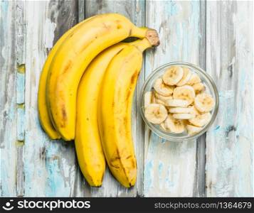 Bananas and banana slices in a glass bowl. On a white wooden background.. Bananas and banana slices in a glass bowl.