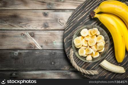 Bananas and banana slices in a glass bowl on the old dressing. On a black wooden background.. Bananas and banana slices in a glass bowl on the old dressing.