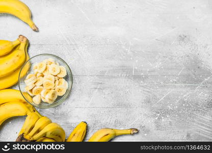 Bananas and banana slices in a glass plate. On white rustic background. Bananas and banana slices in a glass plate.