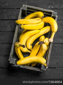 Bananas in the black box. On black rustic background.. Bananas in the black box.