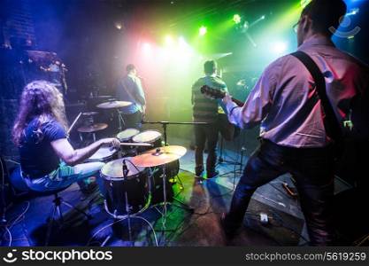 Band performs on stage, rock music concert in a nightclub