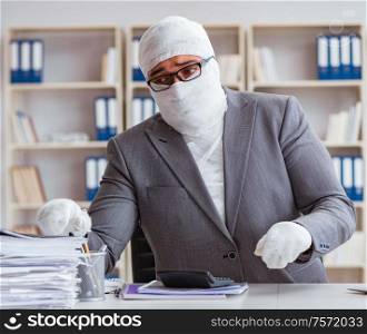 Bandaged businessman worker working in the office doing paperwork. Bandaged businessman worker working in the office doing paperwor