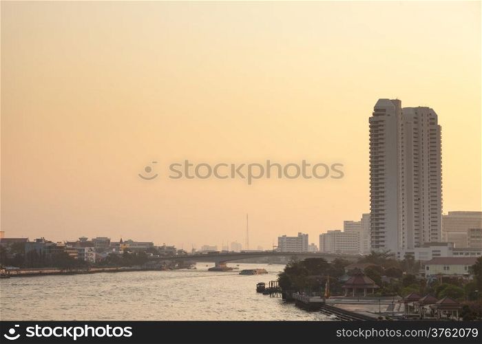 Bangkok city and river in evening. Has high buildings and bridges across the river in the evening.