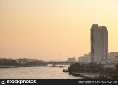 Bangkok city and river in evening. Has high buildings and bridges across the river in the evening.
