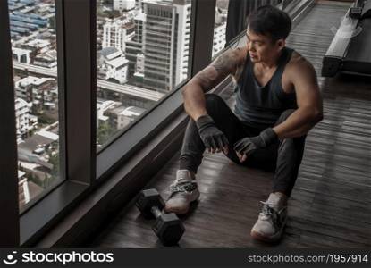 Bangkok, Thailand 06 Oct 2019 : Sport man sitting and resting after workout or exercise in fitness gym. Relax concept. Strength training and Body build up theme.