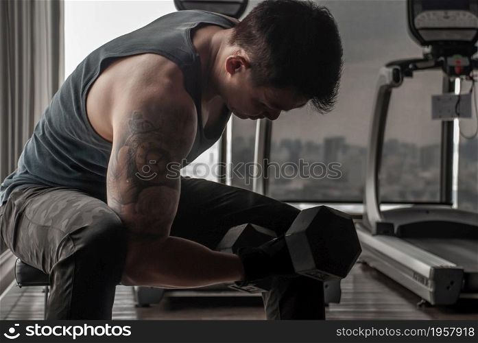 Bangkok, Thailand 06 Oct 2019 : Strong bodybuilder, power athletic man in training pumping up muscles with dumbbell in gym or fitness club.