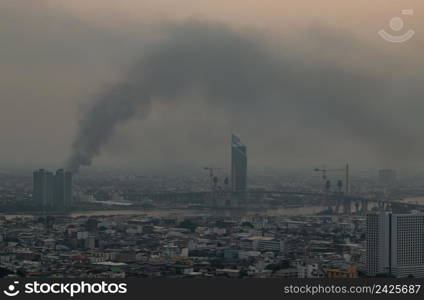 Bangkok, Thailand - 08 Apr, 2022 : Plume of black smoke clouds from Burnt buildings on fire at some area in the bangkok city in the evening. Fire disaster accident, Selective focus.