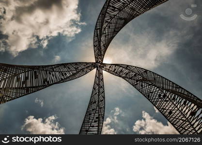 Bangkok, Thailand - 20 May 2021 : Golden steel sculpture for decorative attractive at park. Architectural structure consists of decorative metallic, Photographed from a low angle against a blue sky in the background. Focus and blur.