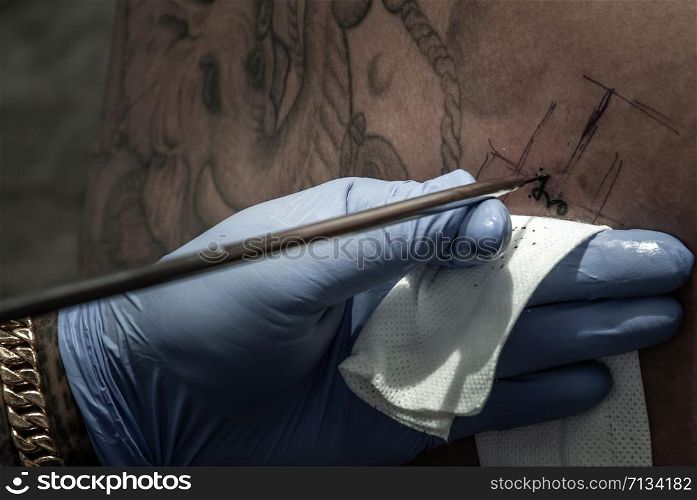 Bangkok, Thailand - 25 Aug 2019 : Tattooing concepts. The artist is tattooing a Thai style pattern on the skin with a pointed metal.