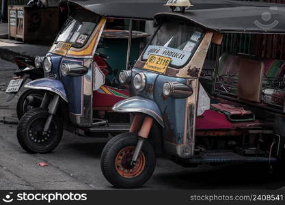 Bangkok, Thailand - Apr 06, 2022 : Famous blue Tuk Tuk or 3-wheeler taxi. Side of Two thai traditional taxi parked in an alley after finishing work, Bangkok street transport, Selective focus.