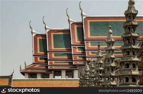 Bangkok, Thailand. Apr - 15, 2022 : Architecture exterior of the chapel with Gable apex roof and Chinese stone sculptures against blue sky at the famous Wat Suthat thepwararam buddhist temple. Selective focus.
