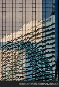Bangkok, Thailand - Apr 22, 2022 : Sky and buidings reflection on Glass wall of building with repeating structure. Exterior architecture of modern building, View from the outside, Copy space, Selective focus.
