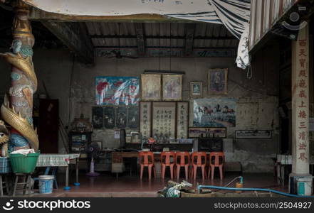 Bangkok, Thailand - Apr 29, 2022 : Architecture interior of Traditional chinese shrine and shrine staff desk with five red plastic chairs Chinese god statues at Phutthamonthon sathan or Sun wukong shrine. Selective focus.