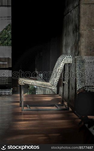 Bangkok, Thailand - Apr 29, 2022   Beautiful sun rays light shining through on the side of design steel chair made of keyboard keys on plaster fron of Bare cement wall. Copy space, Selective focus.
