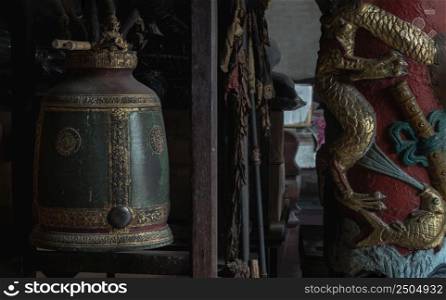 Bangkok, Thailand - Apr 29, 2022 : Sculptured golden dragons red pillar and Traditional old green iron bell hanging in Phutthamonthon sathan or Sun wukong shrine. Selective focus.
