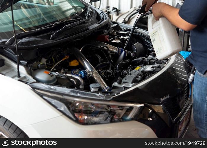 Bangkok, Thailand - April 4, 2020 : Unidentified car mechanic or serviceman cleaning the car engine after checking a car engine for fix and repair problem at car garage or repair shop. Checking a car engine for repair at car garage