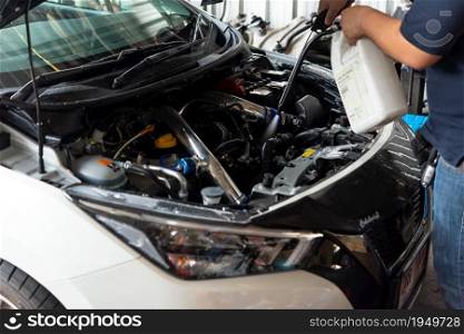 Bangkok, Thailand - April 4, 2020 : Unidentified car mechanic or serviceman cleaning the car engine after checking a car engine for fix and repair problem at car garage or repair shop. Checking a car engine for repair at car garage