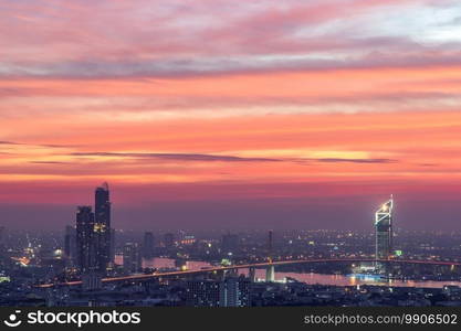 Bangkok, thailand - Dec 23, 2020   Aerial view of Bangkok city Overlooking Skyscrapers and the Bridge crosses the Chao Phraya river with bright glowing lights at dusk. No focus, specifically.