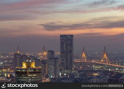 Bangkok, thailand - Dec 23, 2020   Aerial view of Bangkok city Overlooking Skyscrapers and the Bridge crosses the Chao Phraya river with bright glowing lights at dusk. No focus, specifically.