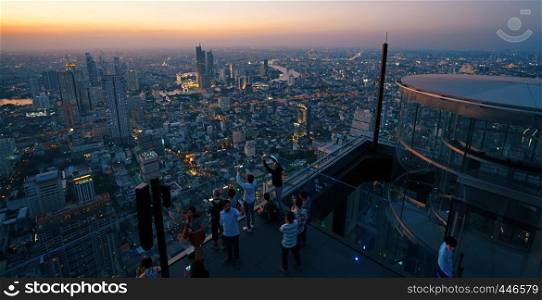 Bangkok, Thailand - December 3 ,2018: Many tourists enjoy sunset on rooftop of the King Power Mahanakhon building high above Bangkok, Famous and tallest building of Bangkok.
