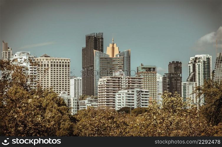 Bangkok, Thailand - Feb 19, 2022 : The View of Modern high buildings among green trees space in nature against blue sky with clouds at afternoon. City growth concept, Selective focus.