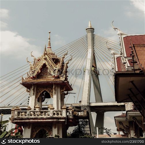 Bangkok, Thailand. Mar - 12, 2022 : Beautiful view of Buddhist thai temple with suspension bridge background can coexist perfectly. Selective Focus.