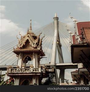 Bangkok, Thailand. Mar - 12, 2022 : Beautiful view of Buddhist thai temple with suspension bridge background can coexist perfectly. Selective Focus.