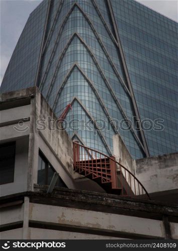 Bangkok, thailand - Mar 18, 2022   Architectural View of Overlapping Modern high building exterior and Old house buildings with Red iron spiral staircase an points of interest. No focus, specifically.