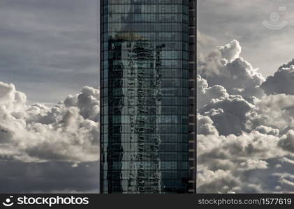 Bangkok, Thailand - Sep 24, 2020 : Angular geometric mirror cladding on a modern building with repeating structure and reflected sky and clouds. No focus, specifically.