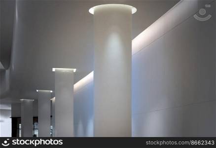 Bangkok, Thailand - Sep 30, 2022 : Concrete interior space with white round pillars arranged long lines lighting cast the shadow on the wall and pillars. Perspective view of Modern architecture, Selective focus.